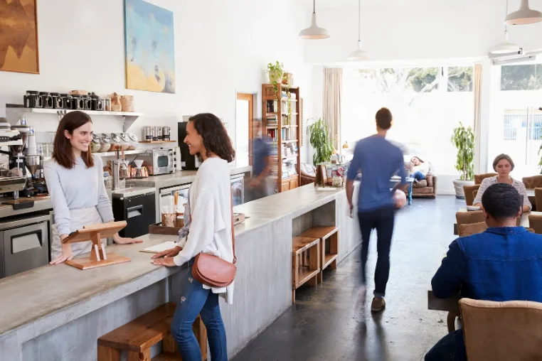 Interior de una cafetería de barrio con clientes en la barra.